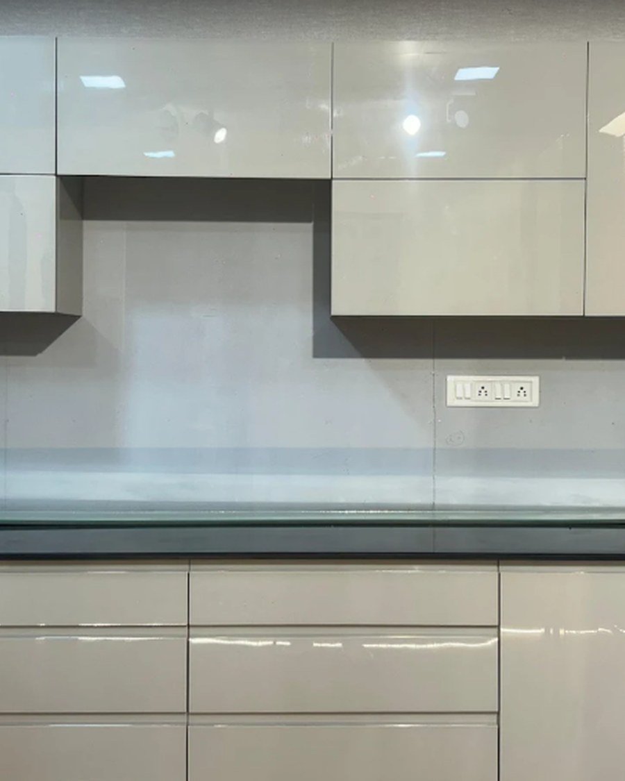 High-gloss white lacquer kitchen cabinetry with concrete-look backsplash