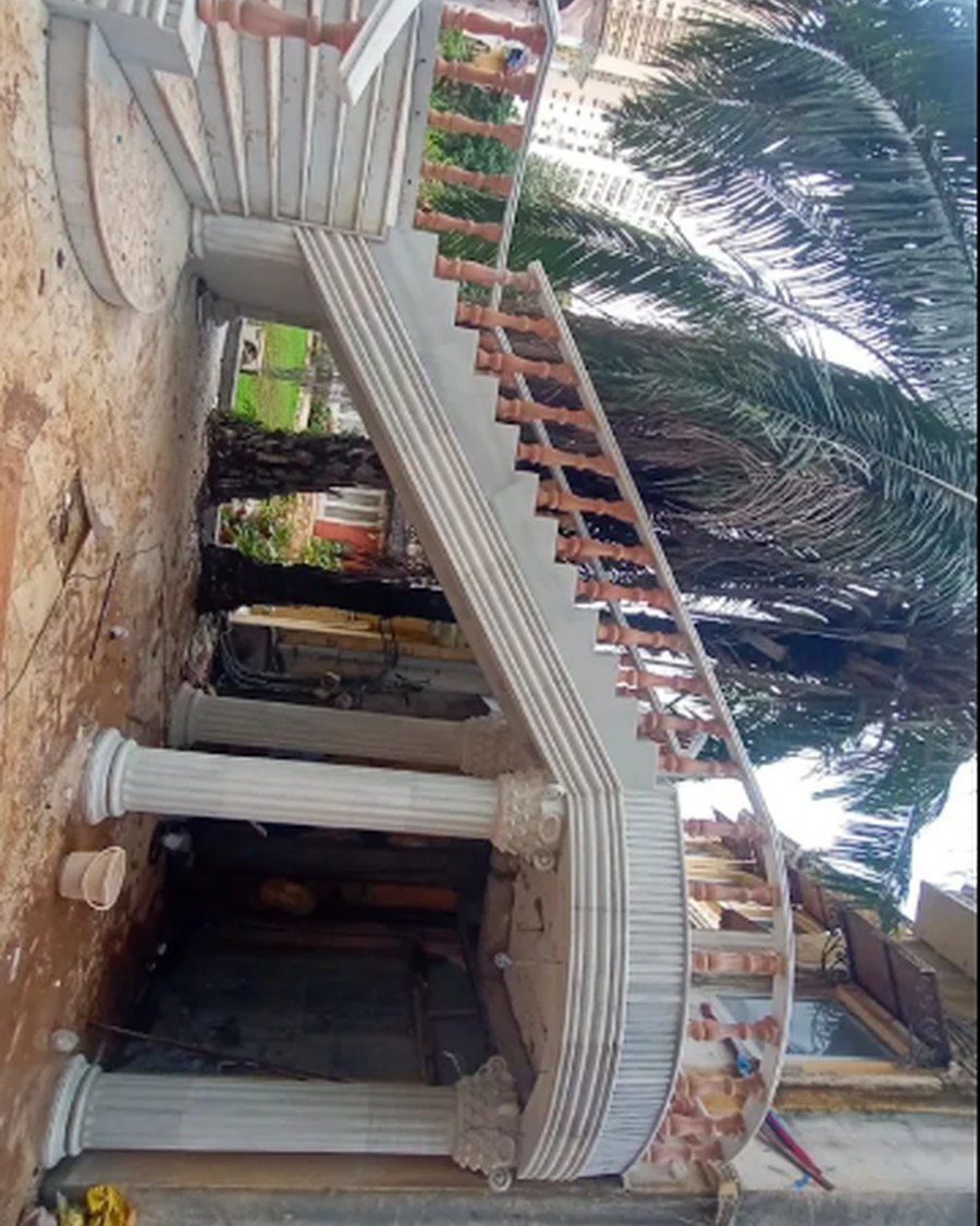 Ornate curved staircase with classical columns under construction on site